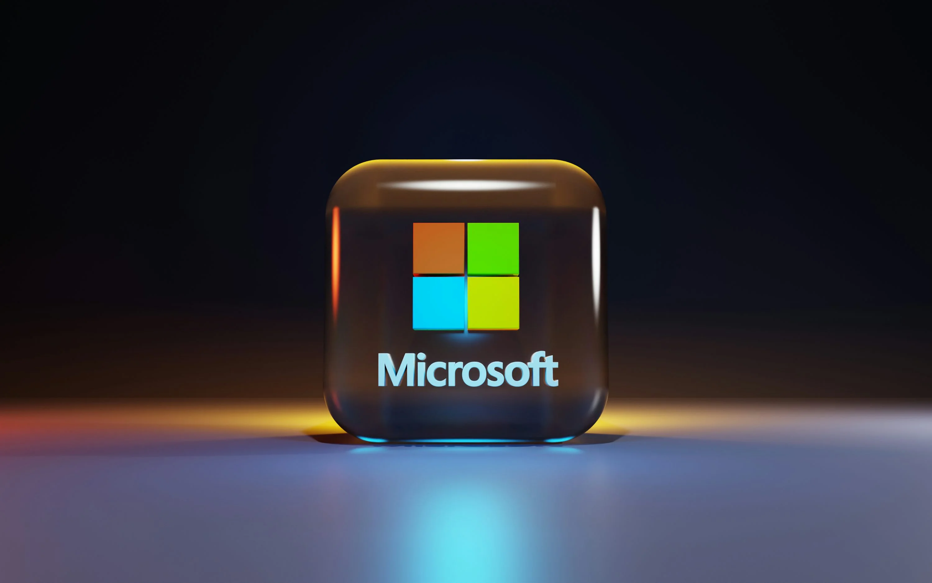 A glossy three-dimensional Microsoft logo cube glowing on a dark reflective surface